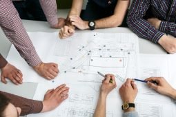 table-with-blueprints-hands-holding-pencils (1)